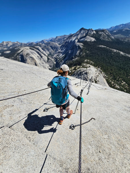 person scaling half dome's cables