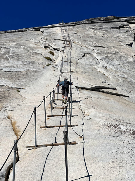 person scaling half dome's cables