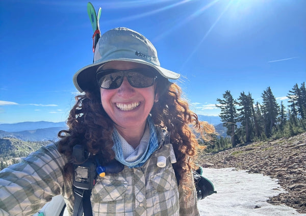 photo of woman hiking with skis on her back