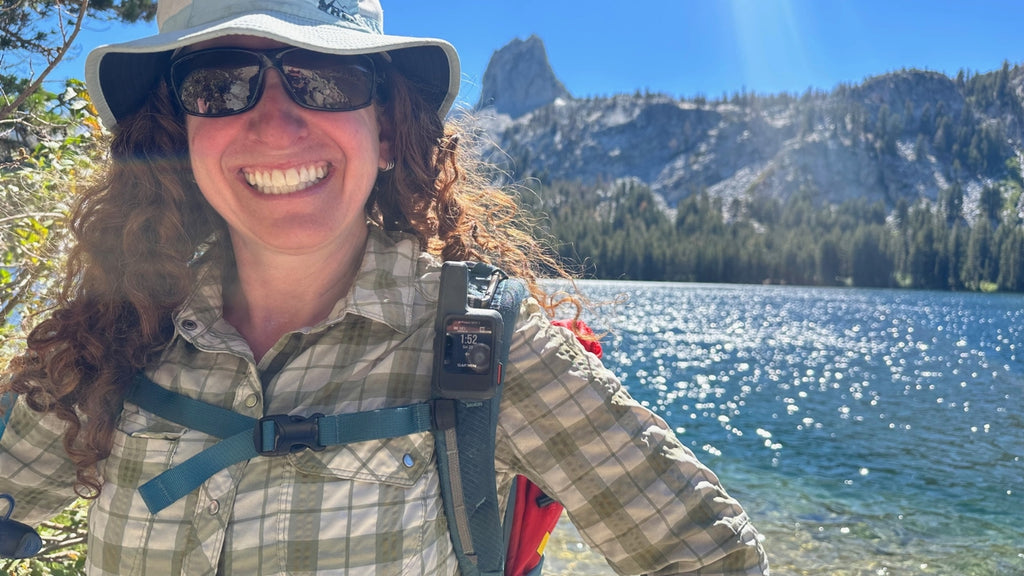 woman taking a selfie with a lake behind her