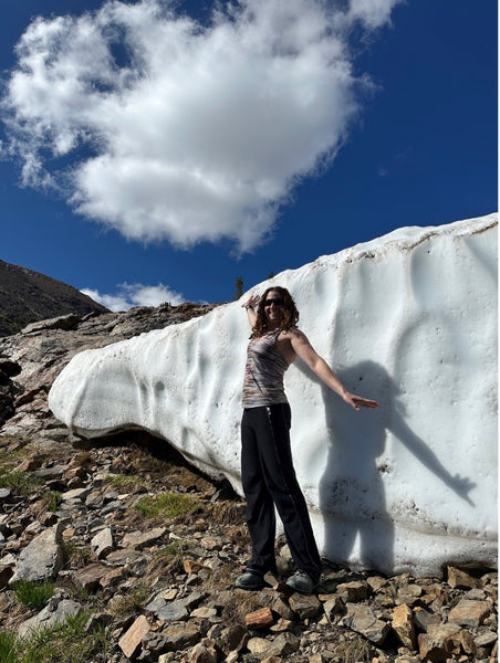person standing next to large snow bank in September
