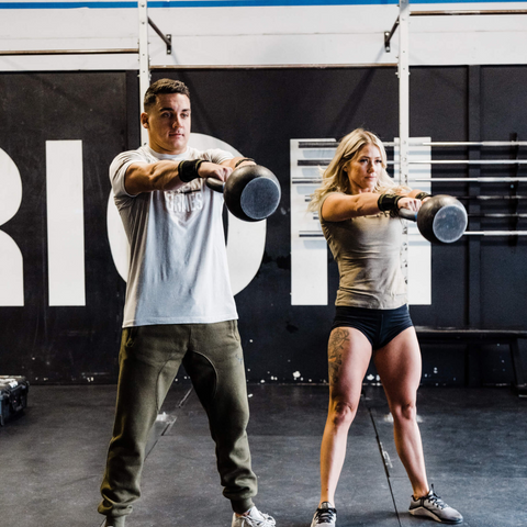 male and female athlete lifting kettlebells