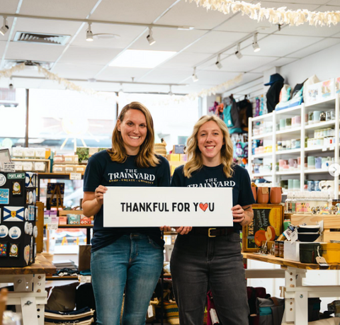 A photo of two Trainyard employees holding a sign that reads "Thanks for you" the 'o' in You is a heart. 