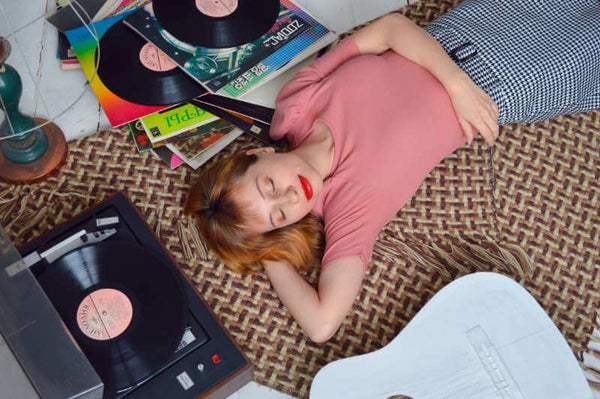 Woman relaxing with her vinyl record collection that she recently cleaned using vinyl record cleaning solutions
