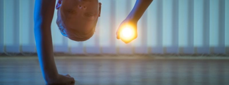 enfant qui regarde sous le lit avec une lampe torche