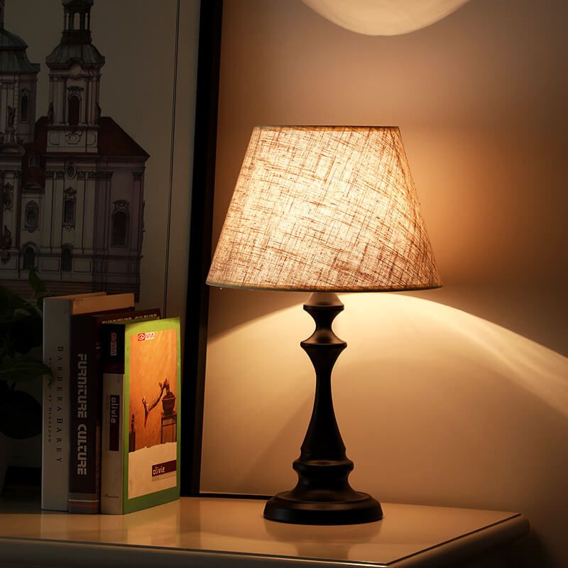 Lampe de chevet blanche et bois nordique allumée sur une table