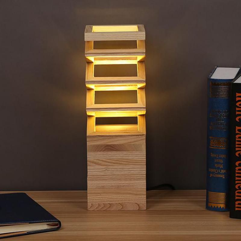 La lampe de chevet en bois de palette allumée à côté de plusieurs livres