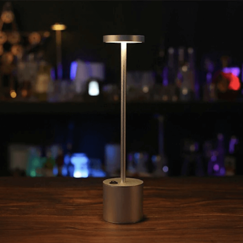 Lampe de chevet liseuse design allumée sur une table