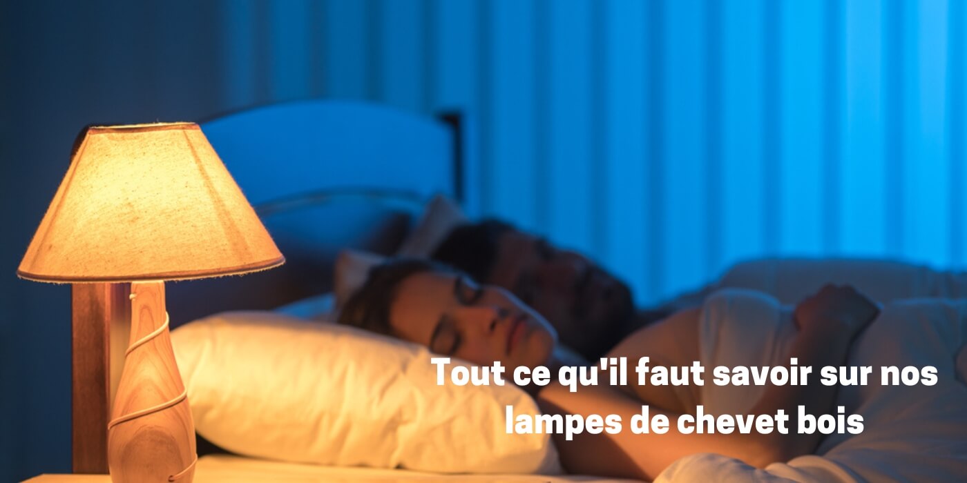 Lampe de chevet bois allumée dans une chambre à coucher, avec deux partenaires qui dorment