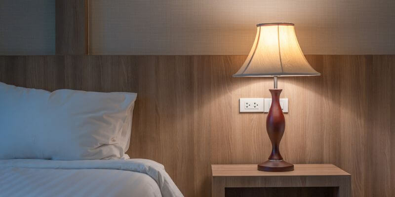 Lampe de chevet bois allumée dans une chambre à coucher