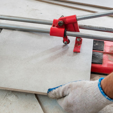 Application image of a tiler cutting tiles with a mechanical tile cutter