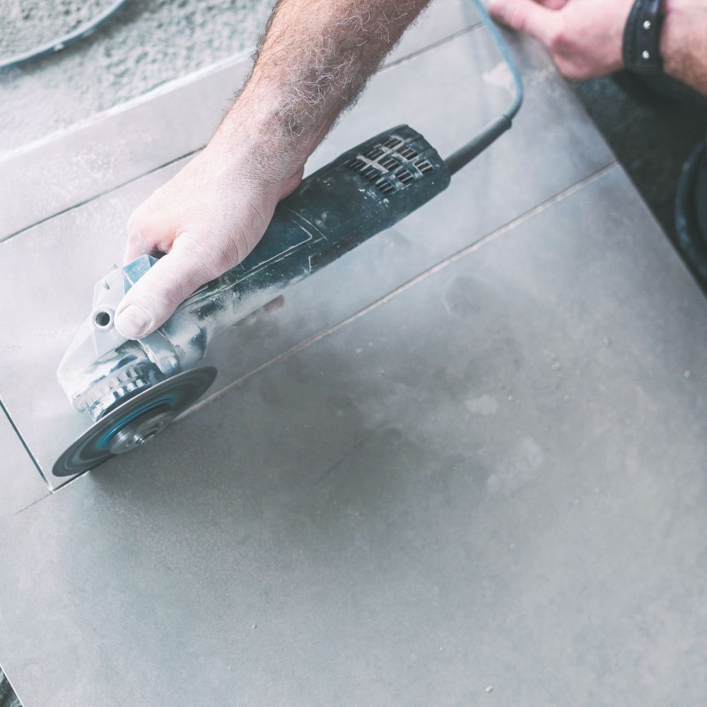 Artisan coupant des évidements dans les carreaux avec la meuleuse d'angle (flex)