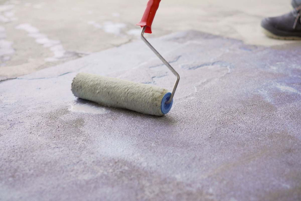 Handyman applying a primer to the floor before tiling as preparation