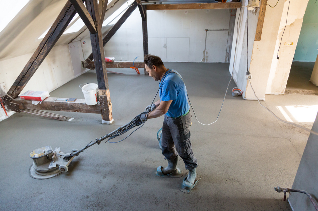 Handwerker beim Estrich schleifen