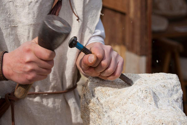 Steinmetz beim Bruchstein bearbeiten mit Hammer und Meißel
