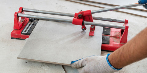 Tiler cutting porcelain stoneware tiles for the floor with a tile cutter