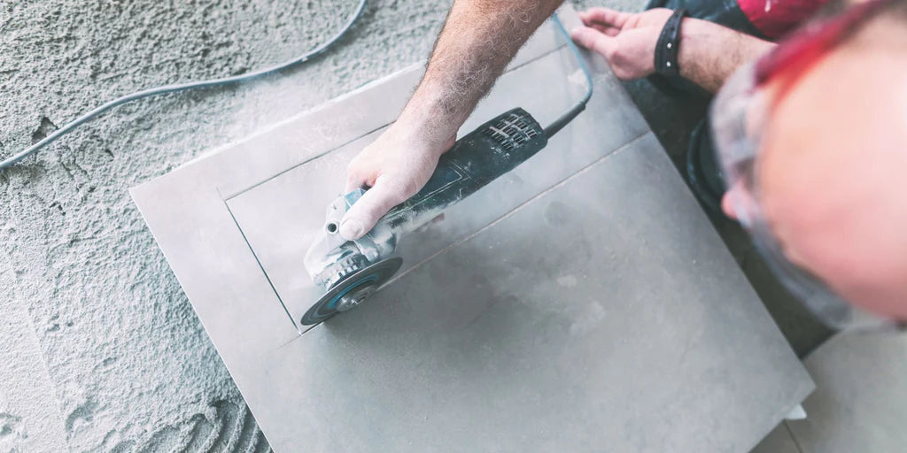 Artisan coupant des dalles de terrasse de 2 cm d'épaisseur avec une meuleuse d'angle et un disque à tronçonner diamanté