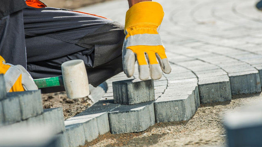 Les courbes sont découpées dans le pavé pour s'ajuster dans la zone d'angle. Bricoleur posant une allée de jardin en pavé uni