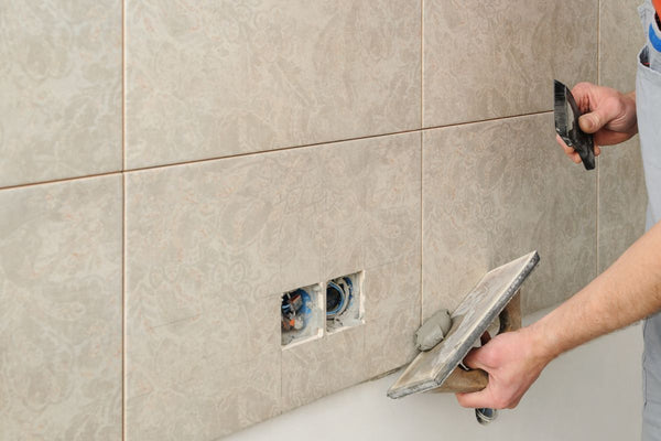 The process of sealing and grouting bathroom tiles is shown.