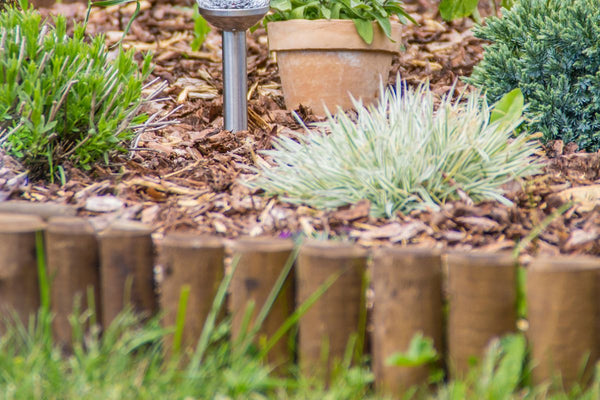 Der Gartenweg aus Rindenmulch wird optisch und physikalisch mit alten Holzlatten abgegrenzt