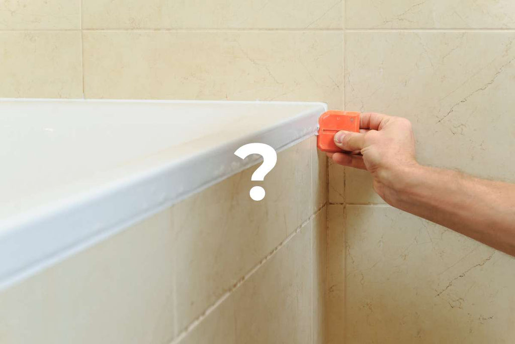 A picture of a tiler cleaning the silicone joints of tiles with a silicone squeegee after grouting