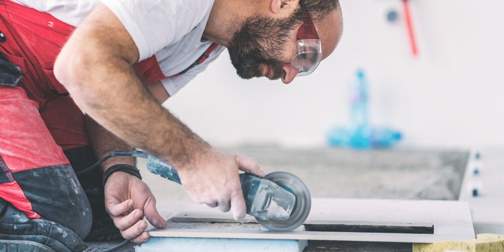 Les bricoleurs découpent des trous dans les douilles avec la meuleuse d'angle et un disque de coupe de carrelage de 125 mm assorti