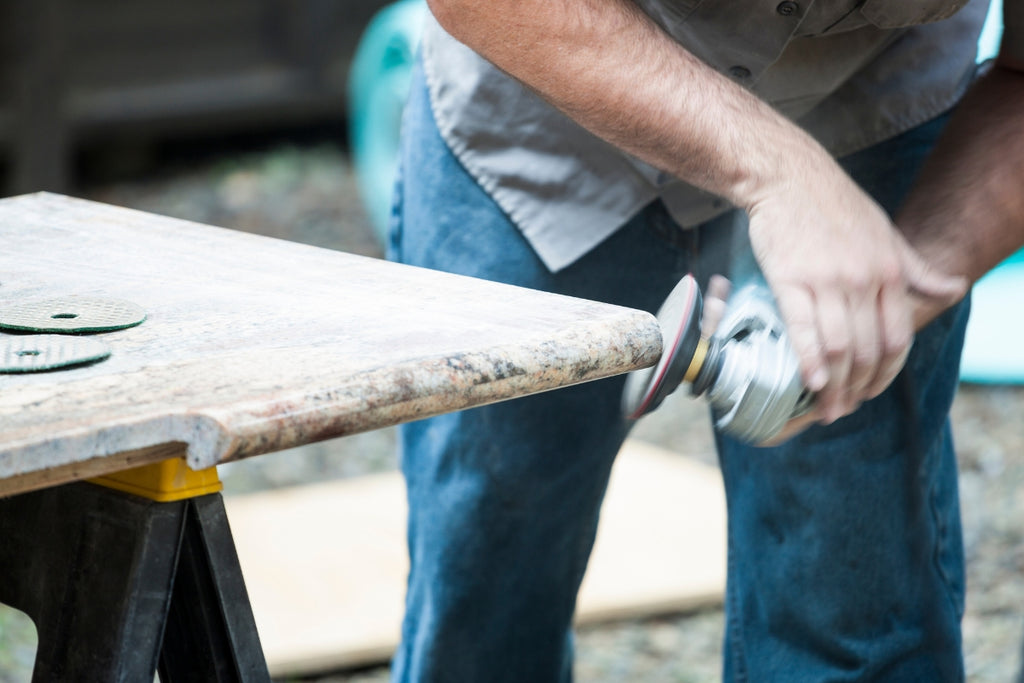 Handyman grinding granite stone with an angle grinder and a diamond grinding wheel