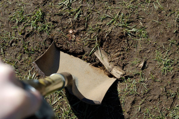 Der Untergrund wird mit einer Schaufel für den Gartenweg aus Rindenmulch vorbereitet