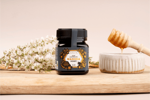 jar of manuka honey mgo 2000 with manuka flowers and honey spoon