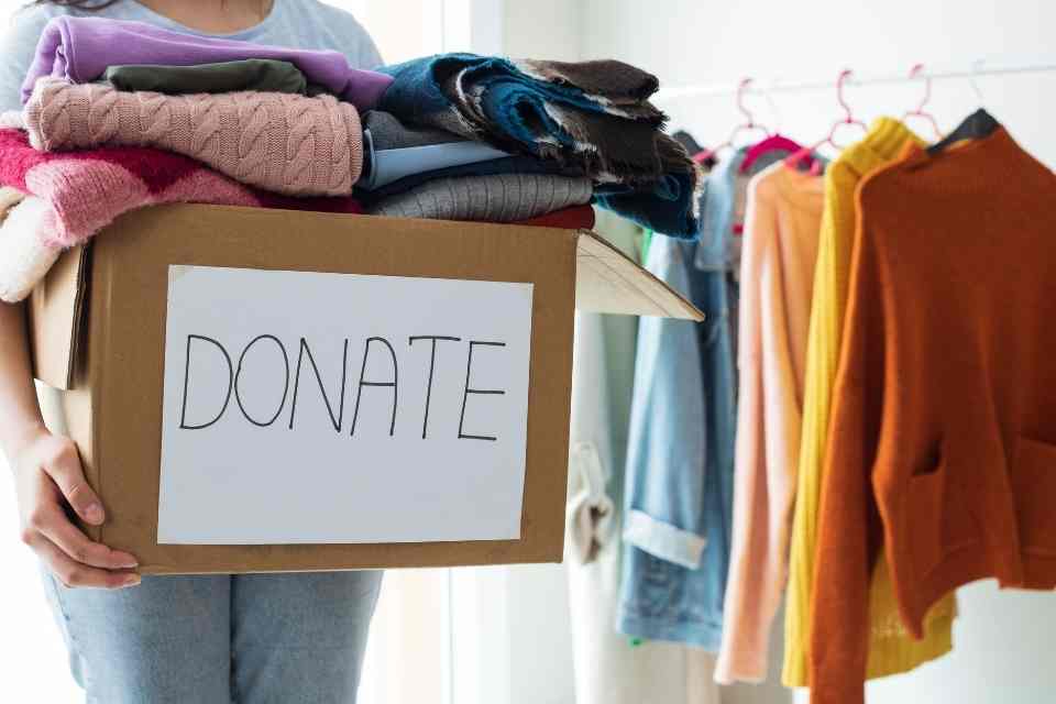 Image of a headless community member with a box of clothes ready to donate