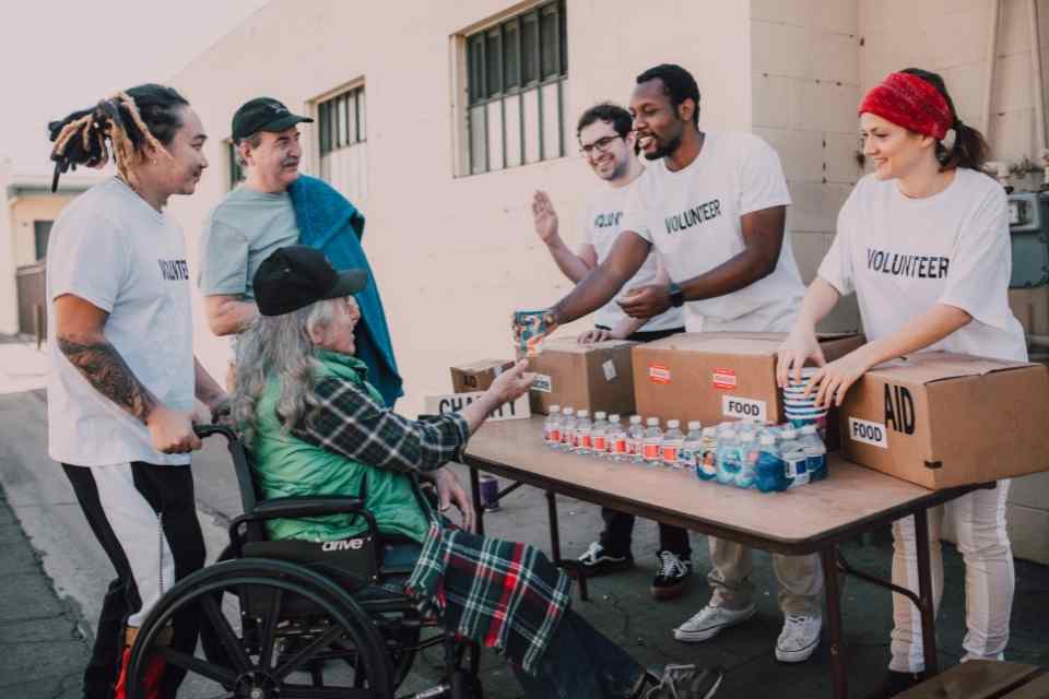 An image of a group of community member volunteers helping struggling community members by handing out food and water