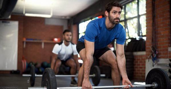 Men deadlifting together in fitness class