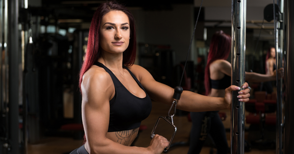 Female bodybuilder performing single-arm cable tricep extensions