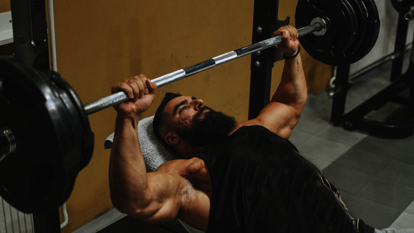 Male bodybuilder bench pressing heavy weights to build endurance and strength.