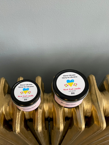 travel size candle next to standard size tin candle. top lid is decorated with label that is made in support of Ukraine. Label includes message "Glory to Ukraine" in Ukrainian and in English. Both candles are natural soy scented candle hand-made in Toronto, Ontario. 