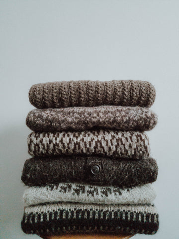 A stack of sweaters handknit in unspun yarn. 