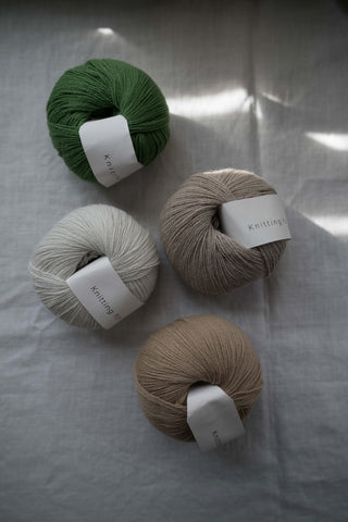 Assorted balls of Knitting for Olive - Merino yarn displayed on a natural background.