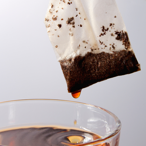 Chai "tea bag" being pulled from a steeped cup.