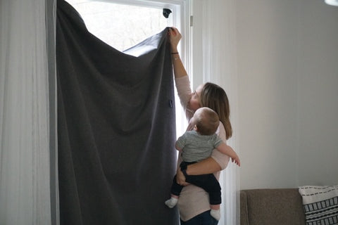 woman with baby putting up high quality blackout curtains