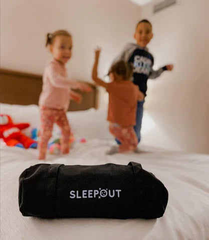 kids jumping on bed with sleepout curtains 