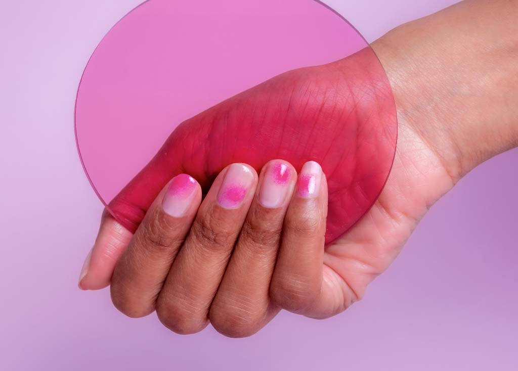 Hand with blush nail art holding a circle prop