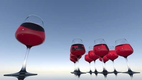 Gläser gefüllt mit Rotwein vor blauem Himmel