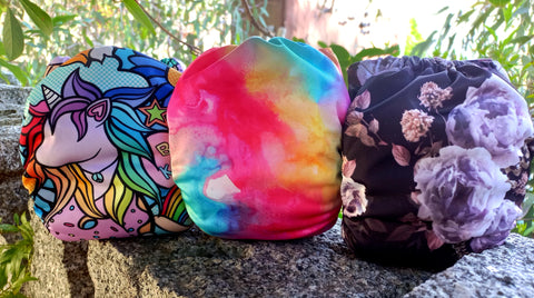 Three brightly coloured nappies on a stone fence.