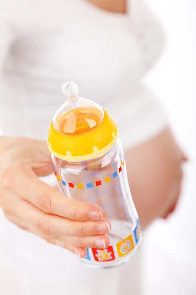 Pregnant woman holding a feeding bottle