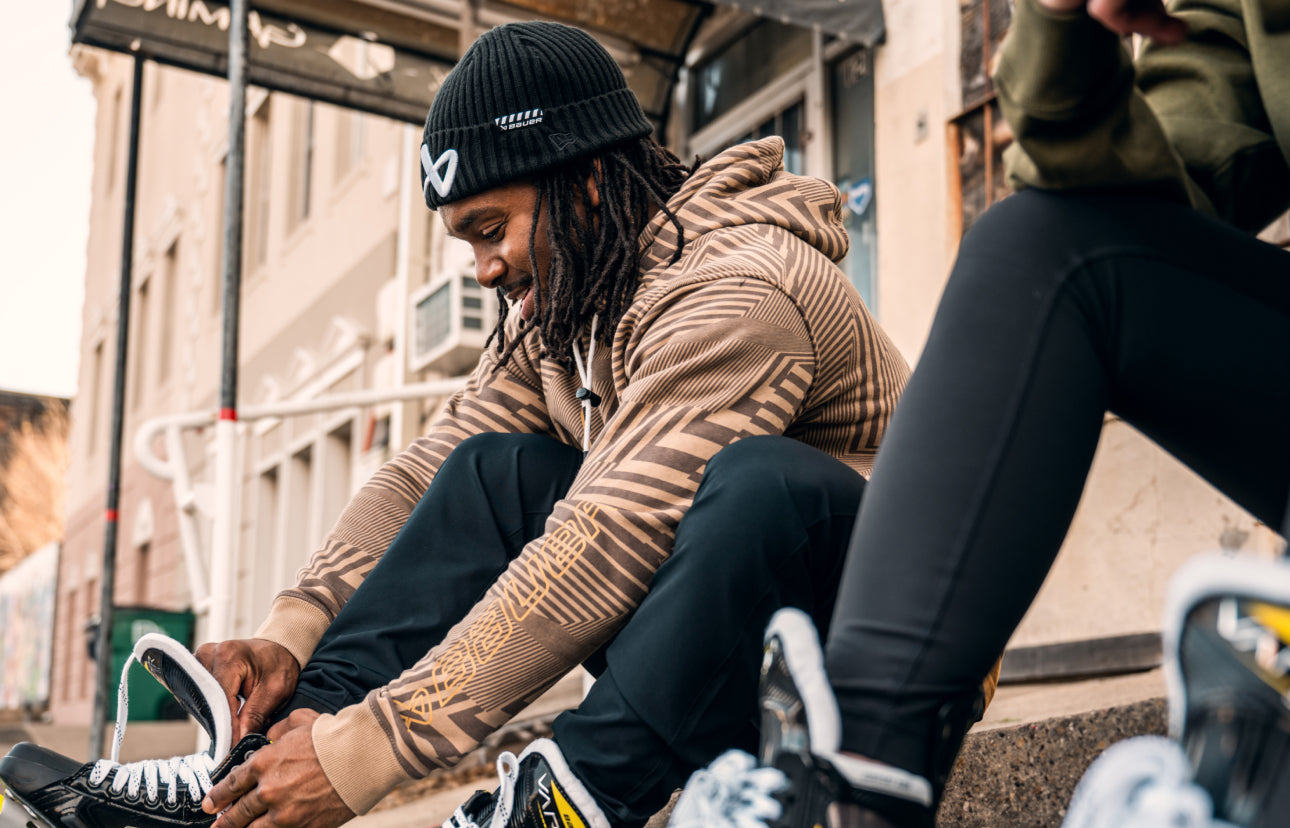 man lacing up roller skates wearing a hoodie and beanie