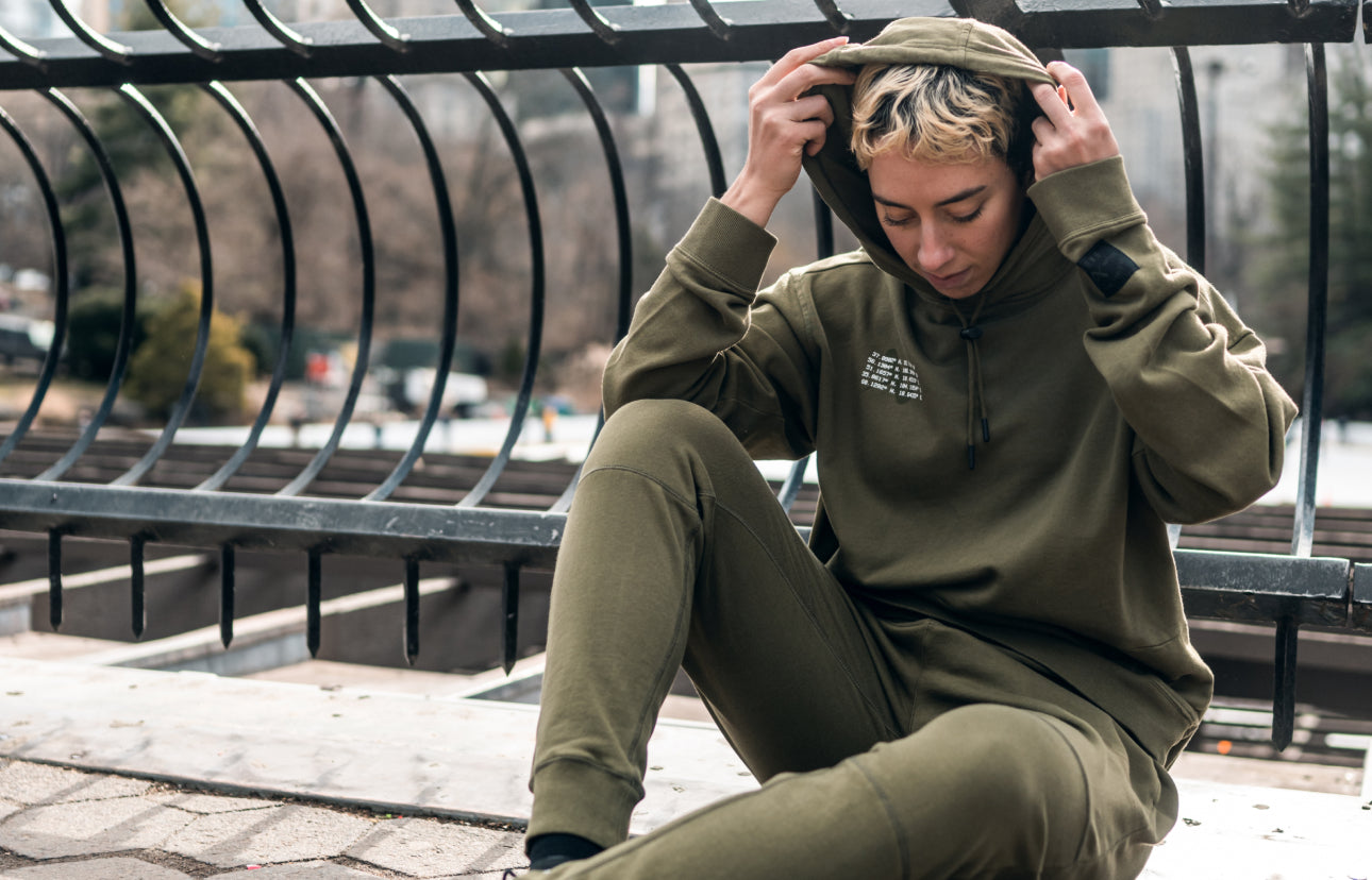 woman in matching green track suit sitting against a metal railing