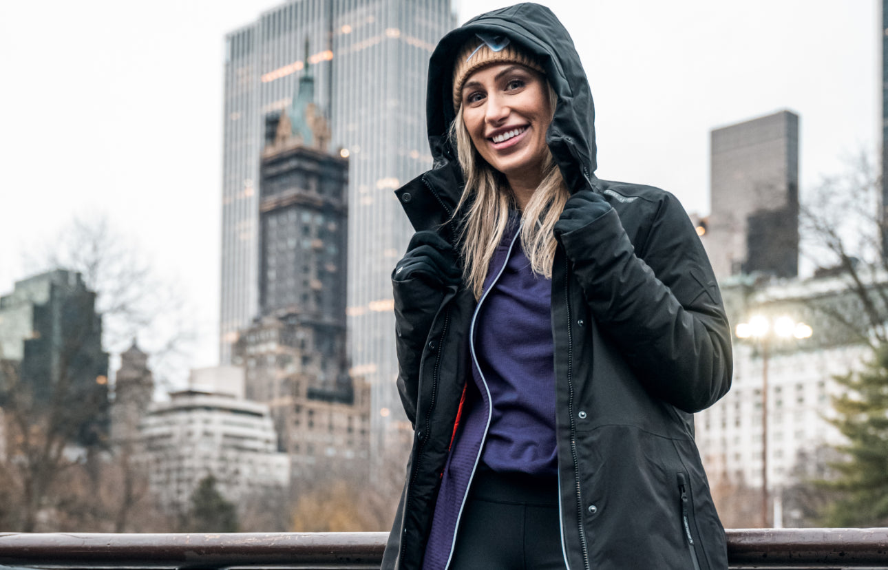 close up of woman smiling in parka with NYC skyline in the background