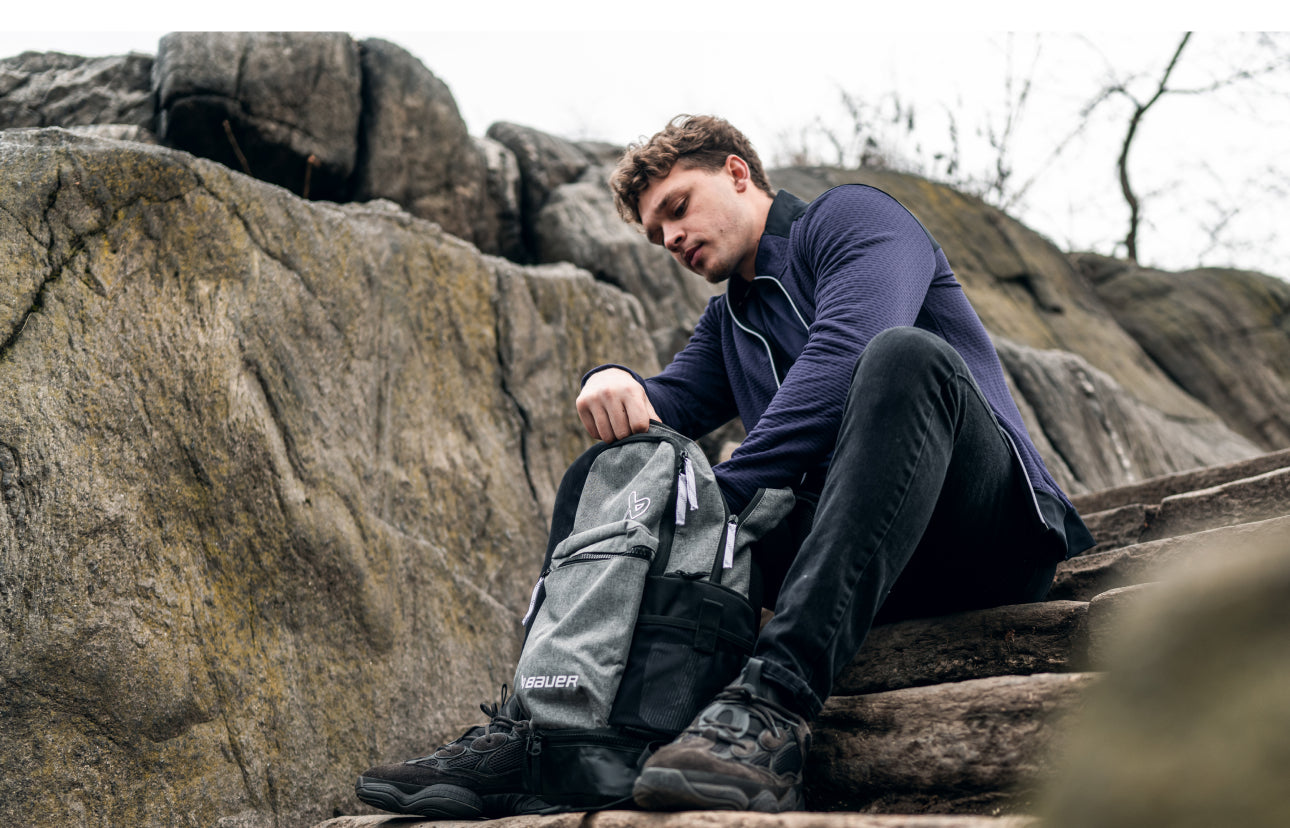 Man sitting on rock steps digging around in a backpack