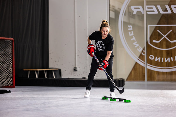 hockey player wearing red gloves practicing hockey skills in a gymnasium