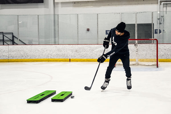 hockey player in hoodie and beanie on the ice shooting the puck